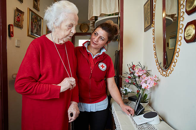 Ältere Dame und DRKlerin vor dem Hausnotrufgerät