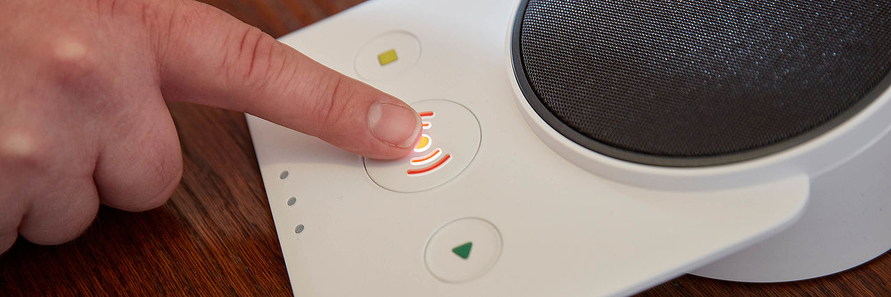 Finger schwebt über der Alarmtaste des Hausnotrufgerät