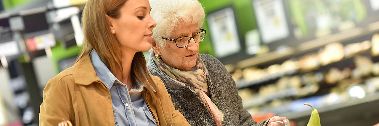 Junge Frau und Seniorin im Supermarkt, bei der Auswahl von Obst